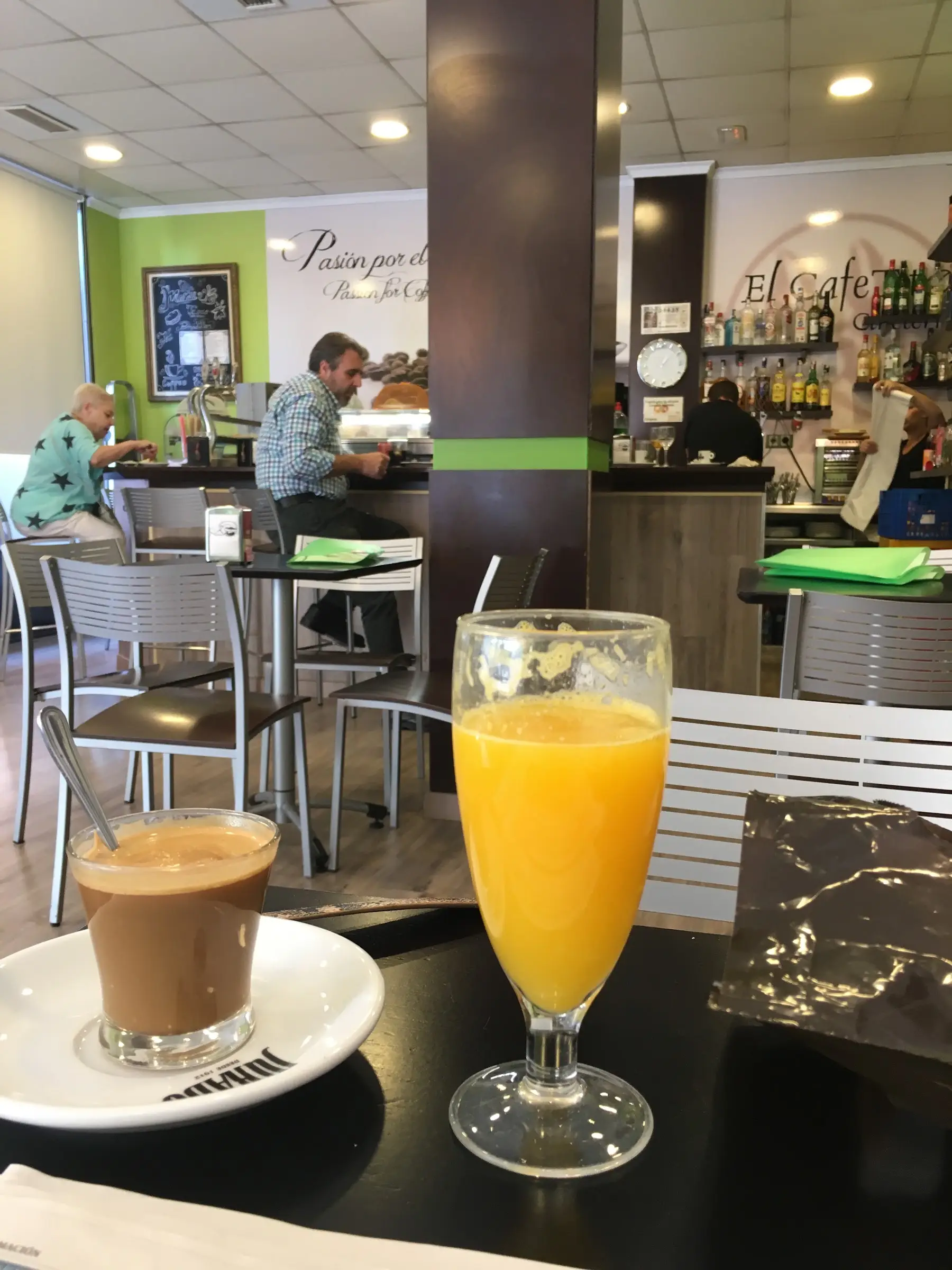 Un café con leche y un zumo de naranja en una mesa del local