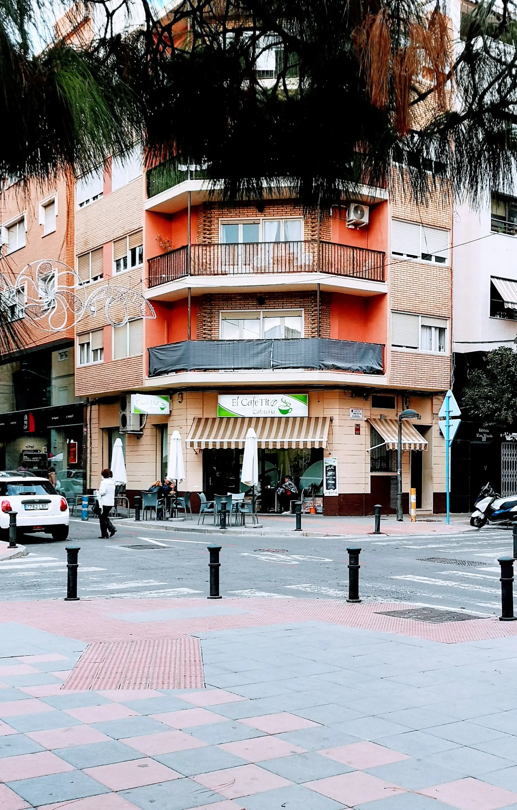 El edificio de la esquina visto desde la acera de enfrente, con el toldo y la terraza en la planta baja