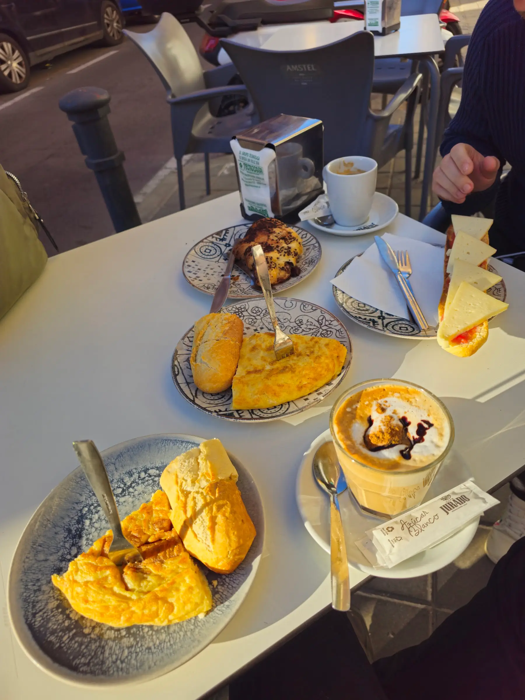 Mesa de la terraza vista desde arriba: tortilla, tostadas y un capuchino